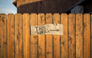 brown wooden plank fence with this way signboard