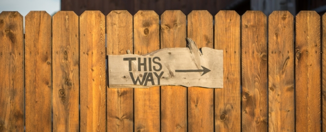 brown wooden plank fence with this way signboard