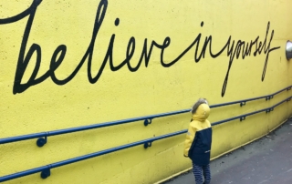 toddler looking at believe in yourself graffiti