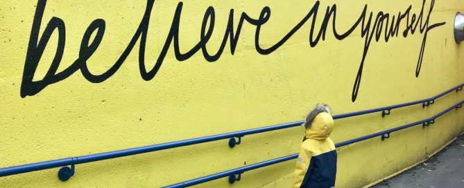 toddler looking at believe in yourself graffiti